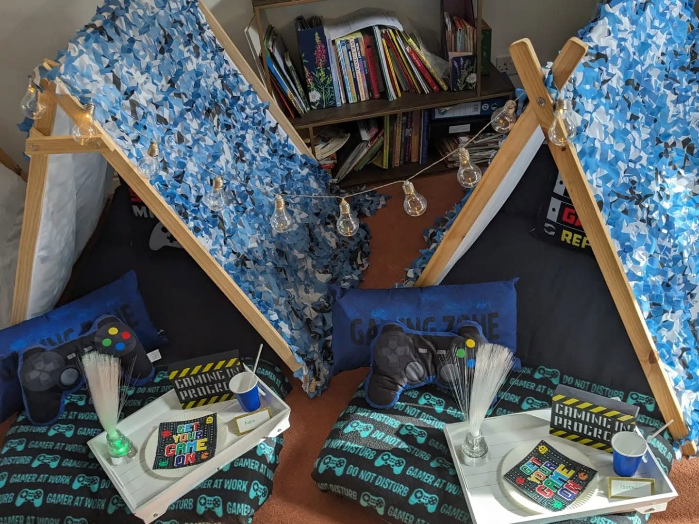 Close view of two blue camouflage gaming teepees with themed blankets and trays