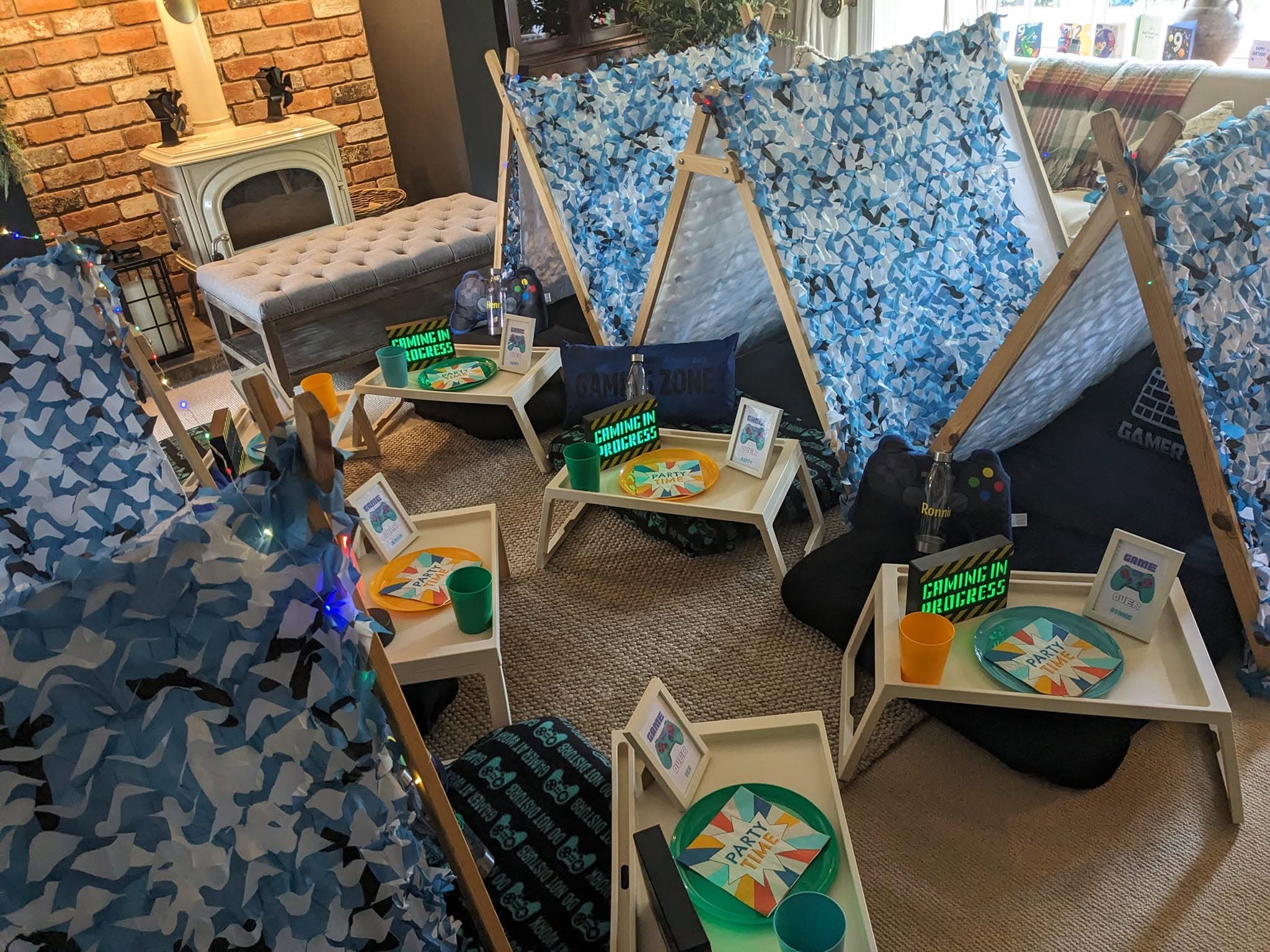 A room of blue camouflage gaming teepees with personalised trays and controller decorations