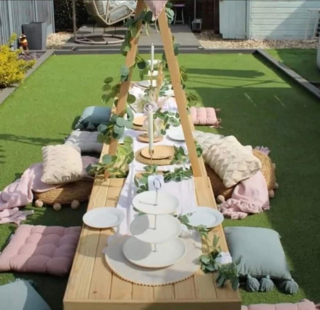 Outdoor low craft table styled with greenery, tableware and pastel floor cushions